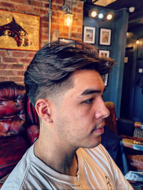 A finished haircut with a close taper and longer swept top